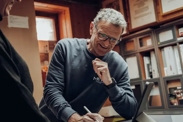 Mann mit Brille berät im Büro am Laptop und macht Notizen im Gespräch