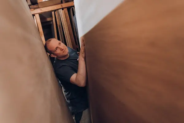 Mann im Lager bewegt große Möbelplatte, Umzug und Möbeltransport Service