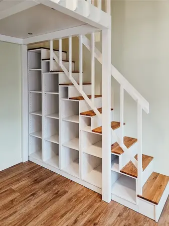 Weiße Holztreppe mit integriertem Regal und Stauraum unter der Treppe