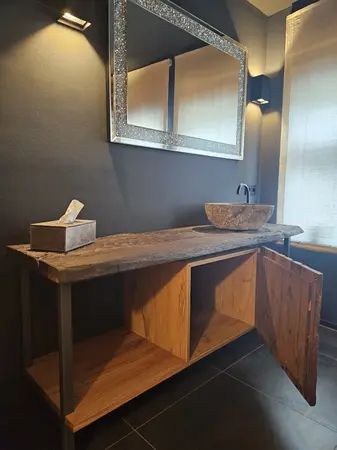 Rustikaler Waschtisch aus Holz mit Steinwaschbecken und Spiegel im Bad